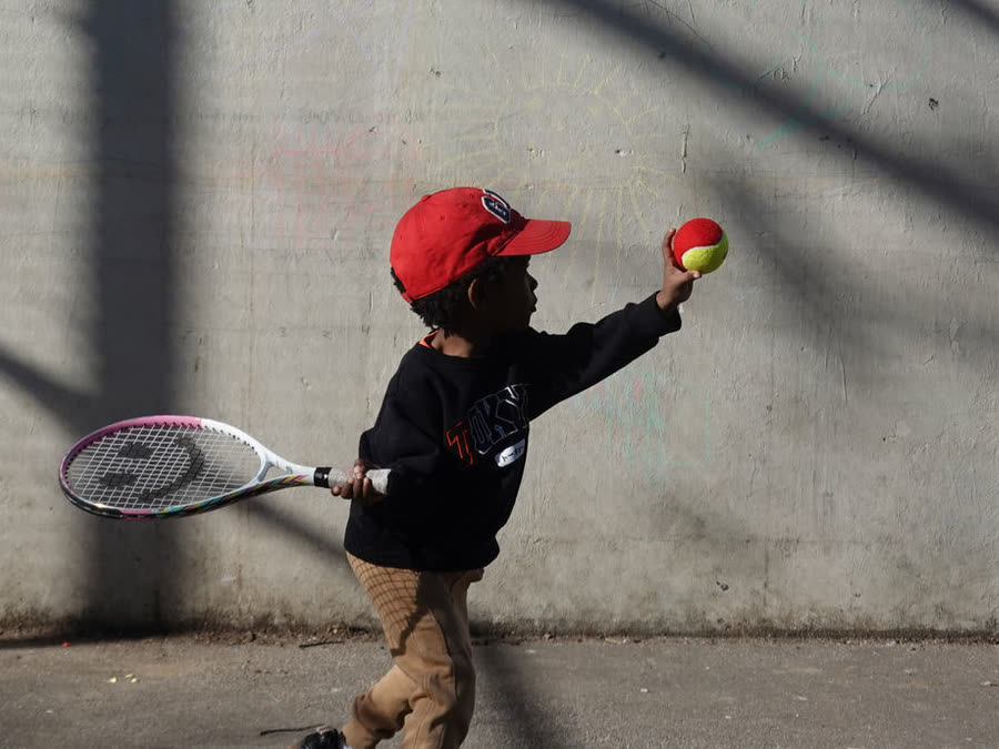 A young player hitting a red ball against a wall